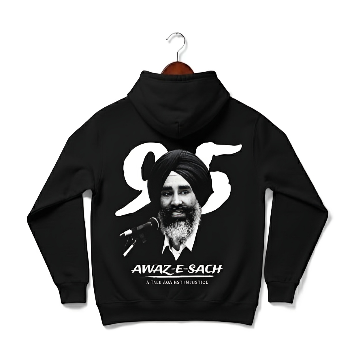Black hoodie with a powerful tribute, featuring a monochrome graphic of a Sikh man with a beard and turban speaking into a microphone, capturing a moment of profound expression. Prominently displayed above him is the bold white number "95," symbolizing a significant year or event. Below the portrait, the text "AWAZ-E-SACH" stands out, translating to "Voice of truth," suggesting a strong message of integrity and justice. Further emphasizing its theme, the phrase "A TALE AGAINST INJUSTICE".