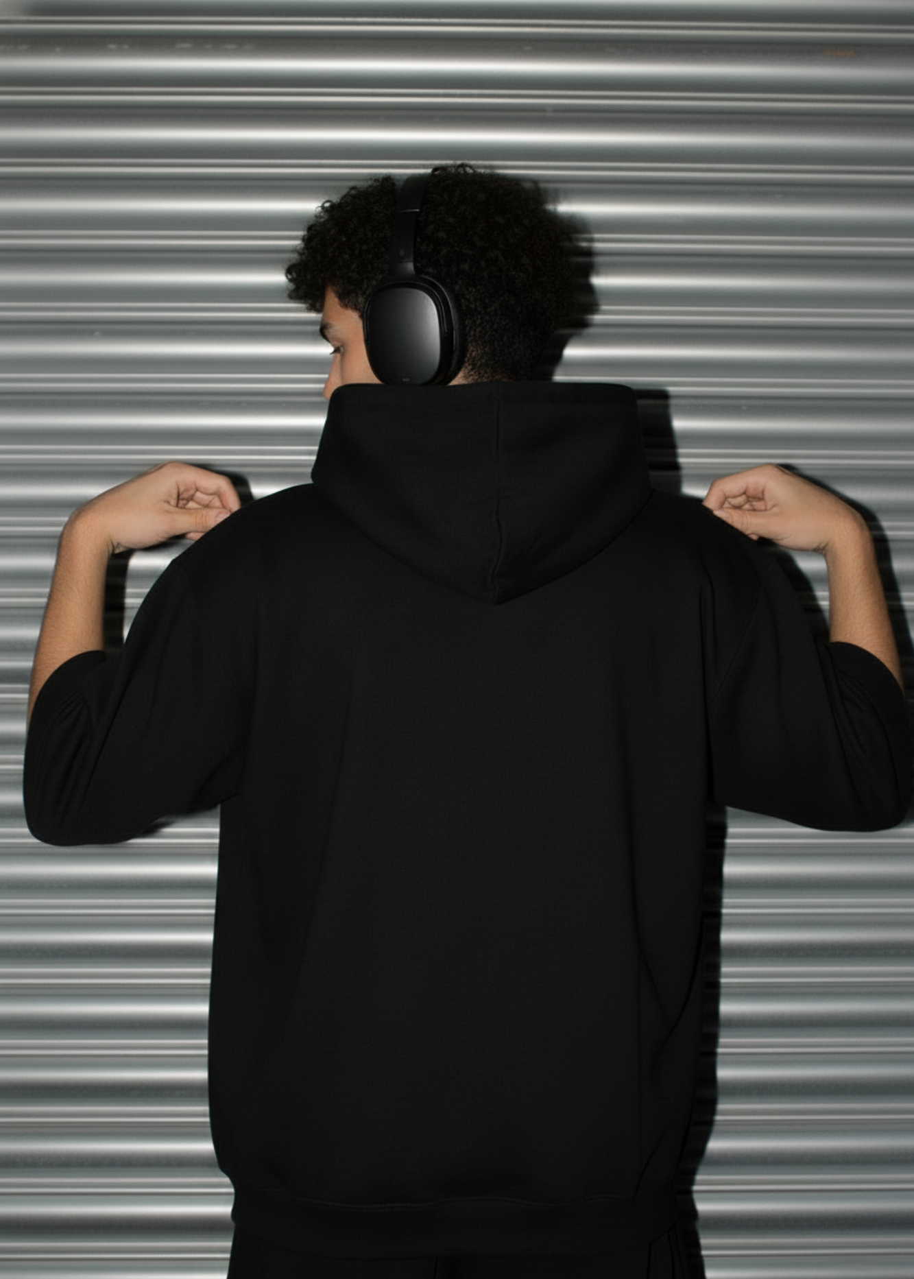 Person wearing a black Cotton Fleece hoodie with a plain background