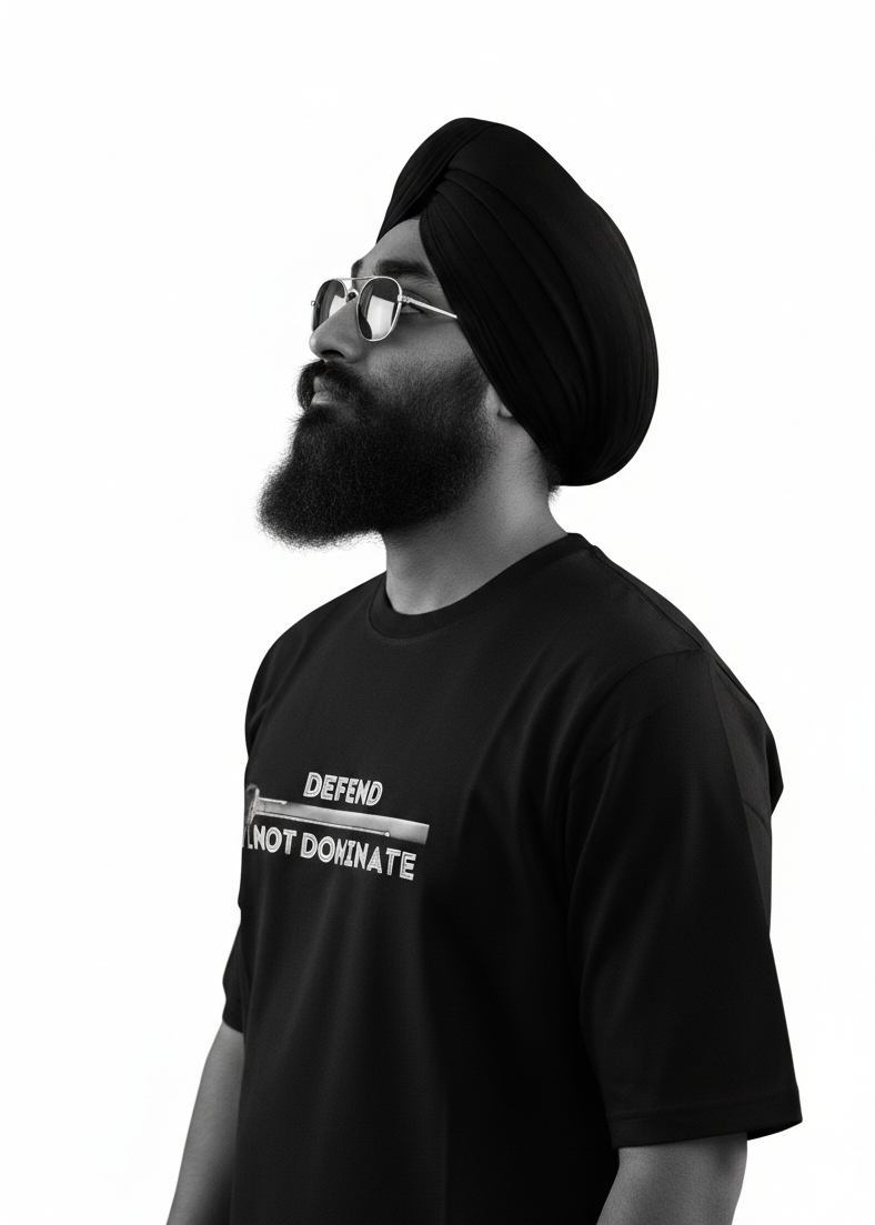 Black turbaned male wearing a black oversized french terry  t-shirt with text (Defend, Not Dominate) with a sword, standing against a white background