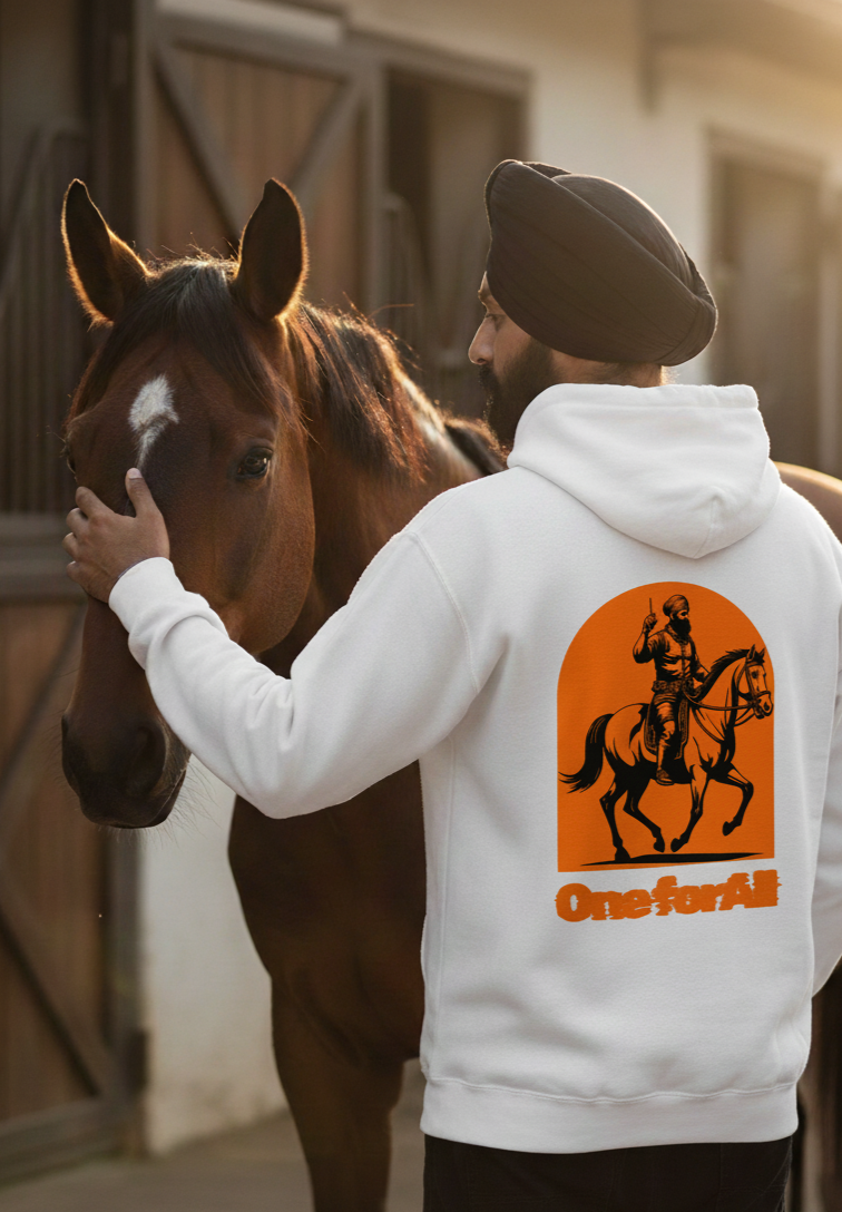 Man wearing a hoodie with a horse and rider graphic, standing next to a horse in an indoor setting.